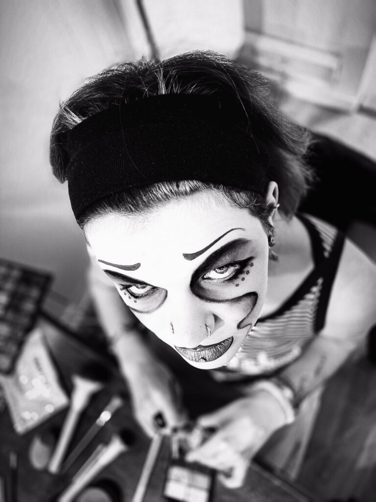 Mascara Spleen capture l’instant où Em, maquillée comme une artiste de cirque, se prépare à affronter ses peurs.