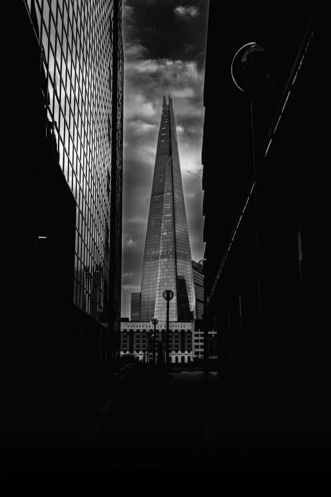 Découvrez Lame du Ciel, une photo en noir et blanc capturant The Shard à Londres. Une œuvre puissante mêlant lumière, ombre et symétrie dramatique.