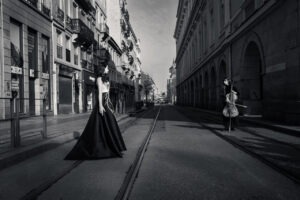 Photo noir et blanc artistique de deux femmes dans une rue vide avec perspective centrale, ambiance cinématographique et tension visuelle.