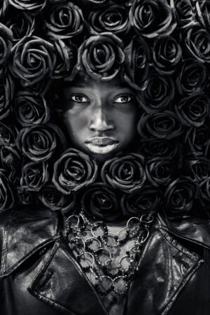 Portrait femme noir et blanc artistique avec fleurs sombres, regard intense, photographie d’art en tirage limité pour décoration murale.