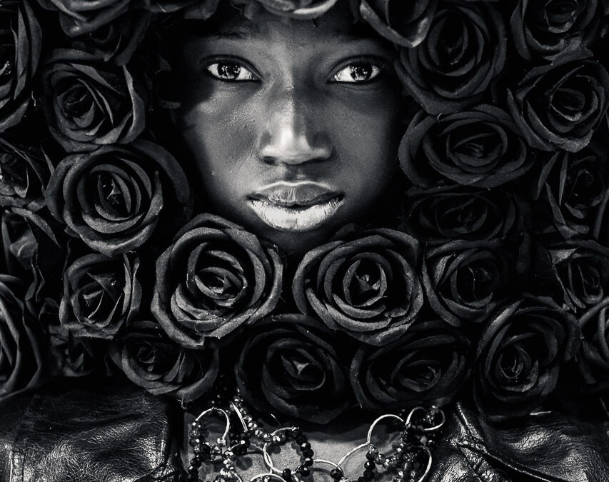 Portrait femme noir et blanc artistique avec fleurs sombres, regard intense, photographie d’art en tirage limité pour décoration murale.