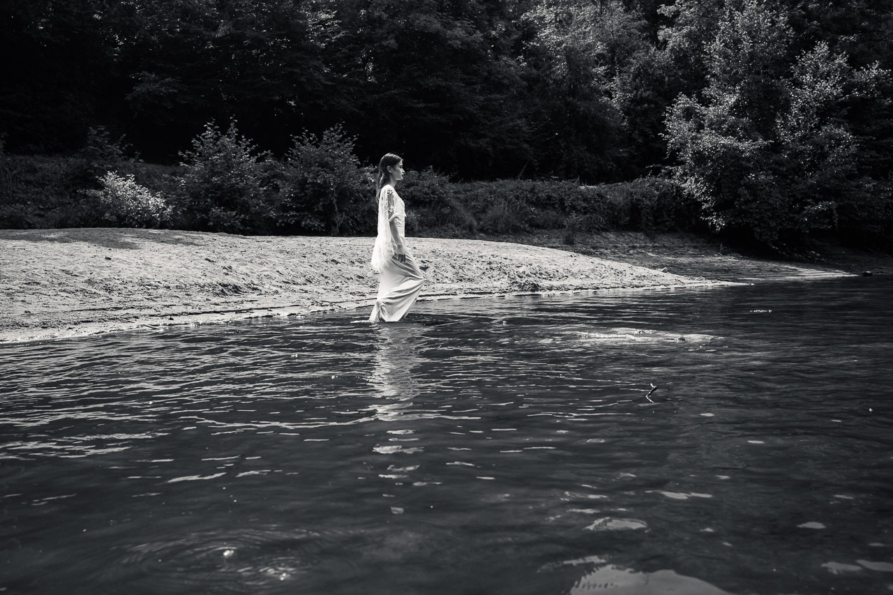 leau-sait-04-entree-dans-eau-thierry-stentzel Femme en robe blanche entrant seule dans l’eau au milieu d’un paysage naturel, photographie noir et blanc